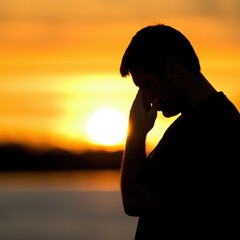 Silhouette of a pensive man against a vibrant sunset backdrop, symbolizing contemplation, solitude, and emotional reflection in a serene natural setting