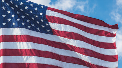 Fototapeta premium A vibrant American flag billowing in the breeze against a bright blue sky, symbolizing national pride and unity.