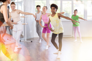 Obraz premium Thin teen boy doing choreography together with other juvenile participants of ballet classes