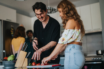 A group of young friends enjoy cooking together in a bright, modern kitchen. They are slicing...