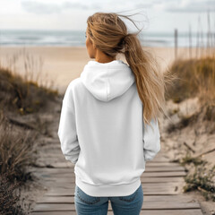 a young female surfer, 25 years old, standing on a beach boardwalk. She is facing away from the...