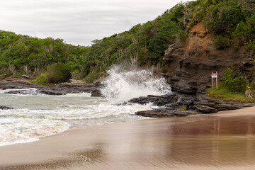 Ola rompiendo en conjunto de rocas a la orilla de playa brasileña