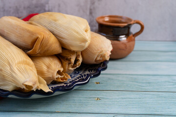 Varios tamales en plato de talavera, taza de barro a lado