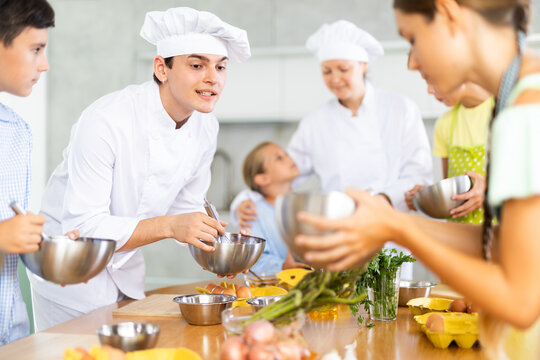 ..Young guy and adult woman chef at master class teaches group of children how to cook food