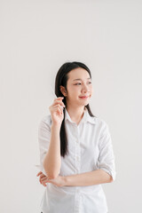 Thoughtful Young Woman Holding Pen in Hand, Wearing White Shirt, Standing Against Plain Background, Contemplating Ideas or Planning, Isolated Indoors