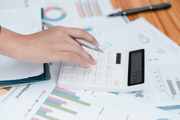 Business Professional Using Calculator on Financial Documents for Data Analysis and Budget Planning in Modern Office Environment