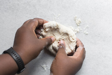 Overhead view of scallion pancake dough being kneaded on a marble countertop, top view of cong you bing dough being kneaded on countertop, process of making scallion pancakes 