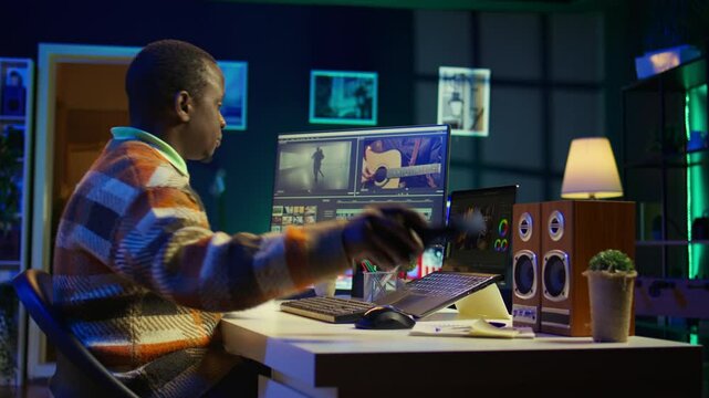 Videographer expert adjusting movie clips on computer at his home, working with color wheel to add visual effects. African american editor making fx montage for video post production. Camera B.