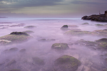 the beautiful view of a tropical beach in the morning, with white sand and coral rocks hit by ocean waves. Landscape images are taken with slow speed technique.