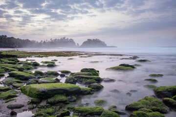 the beautiful view of a tropical beach in the morning, with white sand and coral rocks hit by ocean...
