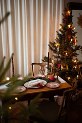 Traditional Christmas stollen fruit cake on festive laying table, preparation for christmas dinner with candles. Christmas tree and fir tree branches on a brown wooden table