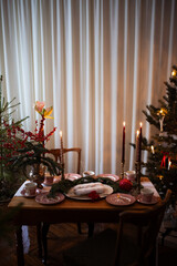Traditional Christmas stollen fruit cake on festive laying table, preparation for christmas dinner with candles. Christmas tree and fir tree branches on a brown wooden table