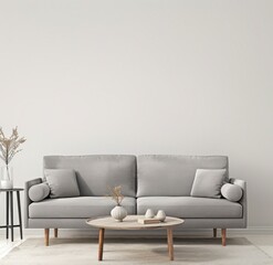 A minimalist living room with a grey sofa, a white coffee table, and a vase with a plant on a side table