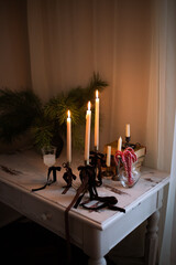Long beige white lighted up candles candles in a candlestick with brown velvet bows. Fir tree...