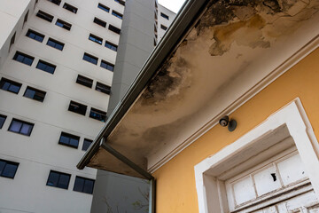 Detail of the facade of an old house with a new building in the background.