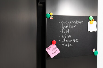 Magnetic board with shopping list and notes on refrigerator in kitchen