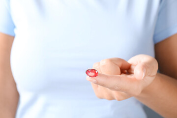 Woman holding one color contact lens, closeup