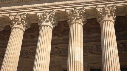 Ornate Corinthian columns with intricate floral capitals support a grand stone facade, highlighting...