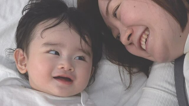 0歳児の赤ちゃんと横になり一緒に遊ぶお母さんのクローズアップの俯瞰、固定撮影
