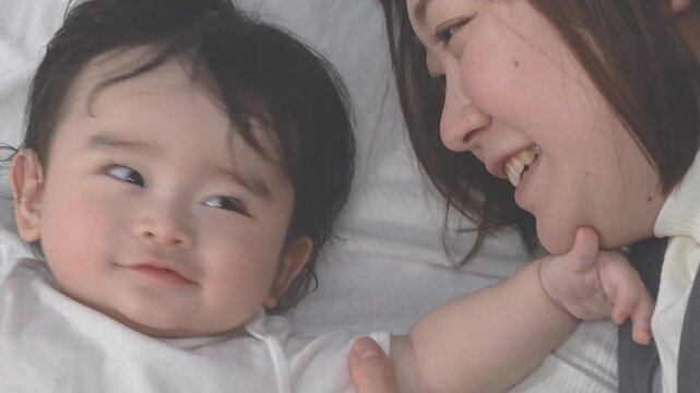 0歳児の赤ちゃんと横になり一緒に遊ぶお母さんのクローズアップの俯瞰、固定撮影