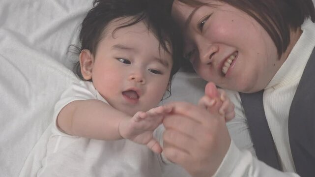 0歳児の赤ちゃんと横になり一緒に遊ぶお母さんのクローズアップの俯瞰、固定撮影