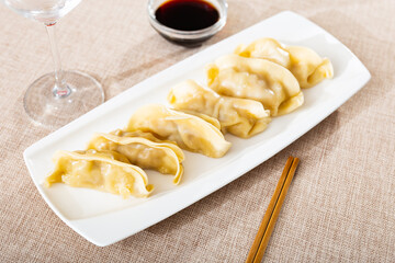 In oriental restaurant, delicious boiled gyoza dumplings, supplemented with necessary chopsticks and spicy soy sauce. Festive dish serving, eating out, concept of tasty, healthy, healthy varied food