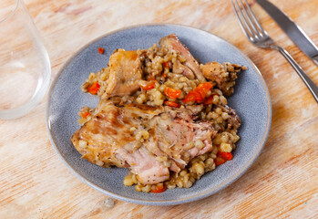 Traditional pearl barley porridge with stewed vegetables and fried rabbit on a plate