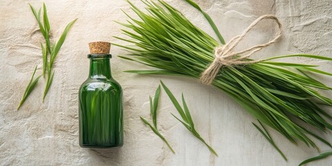 Fresh wheatgrass, a bottle, and twine on a light backdrop.