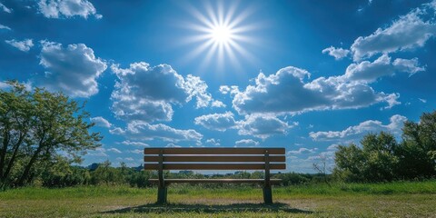 Obraz premium Back view of a bench under a bright sun and a partly cloudy blue sky above.