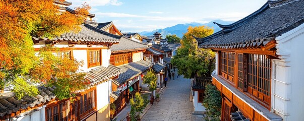 Fototapeta premium A picturesque old street lined with traditional houses, vibrant foliage, and scenic mountains in the background, capturing the charm of historic architecture.