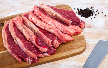 Raw juicy marbled beef steaks with condiments ready for cooking on wooden table..