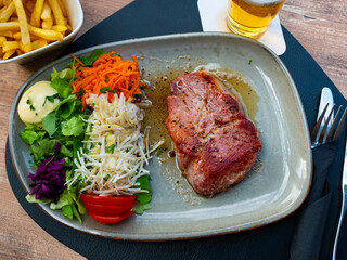 Piece of fried pork in sauce. Served with finely chopped carrots, lettuce, tomatoes and french fries. Belgian cuisine