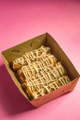 Crunchy banana cake, sweet banana cake with sweet topping, banana cake in a box and pink background