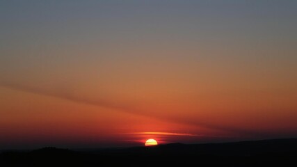 A beautiful landscape where the sun is setting on one side of the sky while the moon rises on the other, creating a stunning meeting of the day and night, nature, peaceful