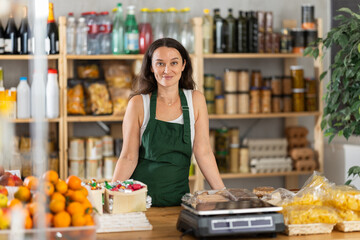 Portrait of female seller in an apron behind the counter of a grocery store