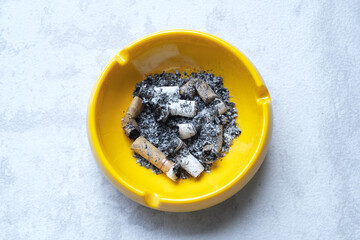 The yellow ash tray filled with cigarette butts
