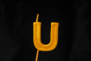 close up on gold Letter U birthday candle on a dark background.  © Sesat_pictures