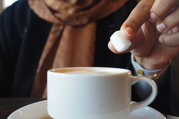 A Sugar Cube Delicately Being Added to a Warm Cup of Coffee, Enhancing the Experience