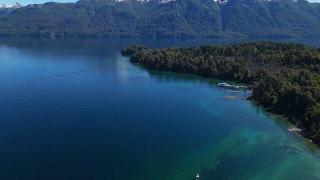 aerial view of Lynch Bay in the Arrayanes Forest, located within Nahuel Huapi Lake in Patagonia, Argentina. The pristine blue waters contrast with the lush green forest, creating a serene and pictures