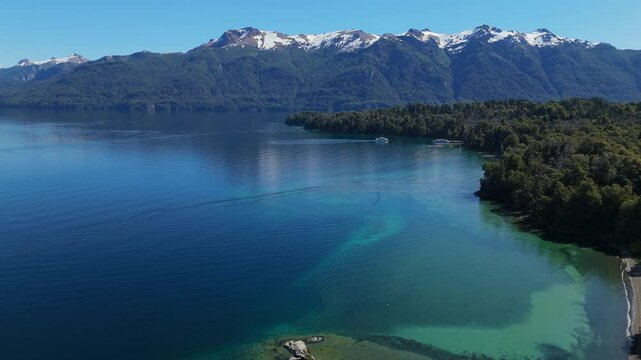 aerial view of Lynch Bay in the Arrayanes Forest, located within Nahuel Huapi Lake in Patagonia, Argentina. The pristine blue waters contrast with the lush green forest, creating a serene and pictures
