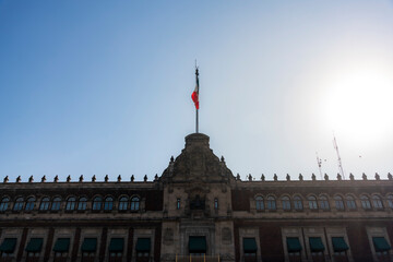 The National Palace, located in front of Zocalo Square in Mexico City, featuring historic architecture and the Mexican flag under sunlight.