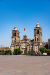 Obraz premium The Metropolitan Cathedral in Mexico City’s Zocalo Square with the Mexican flag, showcasing historic architecture and a vibrant urban setting.