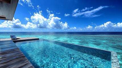 Obraz premium Infinity pool overlooking turquoise ocean and blue sky with fluffy clouds.