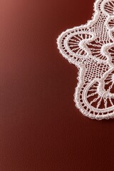 Obraz premium A delicate white lace trim rests on a rich brown surface, showcasing intricate patterns and textures that enhance the overall aesthetic.