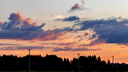 Real majestic sunset or sunrise sundown sky background with gentle colorful clouds without birds over forest.