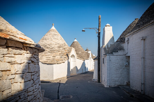 Paisaje urbano con incre&iacute;ble arquitectura t&iacute;pica de truli con hermosos tejados iluminados por el sol en la regi&oacute;n de Puglia, cerca de la ciudad de Alberobello, en el sur de Italia. C&aacute;lida ma&ntilde;ana de ve