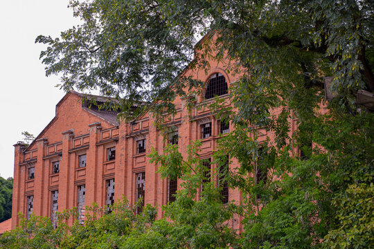 The abandoned building of Engenho Central in Piracicaba, SP, Brazil. The aged brick walls and arched windows evoke historical charm, set against a naturally overgrown backdrop.