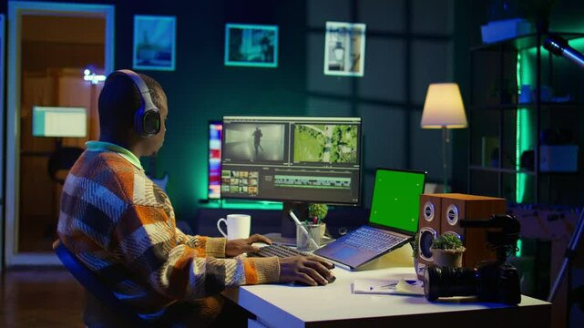 Videographer creating visual effects on montage next to green screen, working on color correction to edit footage and frames. Freelancer content creator editing clips on computer software. Camera B.