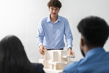 Architects engineers collaborating on building design project in modern office, diverse team of professionals female muslim architect and male engineers discussing architectural model of structure