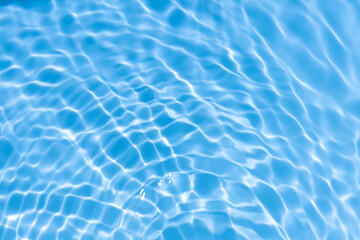 Blue water with ripples on the surface. Defocus blurred transparent blue colored clear calm water surface texture with splashes and bubbles. Water waves with shining pattern texture background.